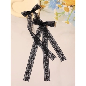 Detail of two black floral lace bow hair clips with long elegant ribbon streamers