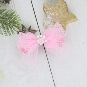 Elegante fermaglio per capelli in pizzo rosa con stella di strass su fondo in legno bianco