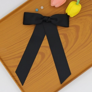 Détail d'un nœud papillon en ruban gros-grain noir avec de longs rubans sur un plateau
