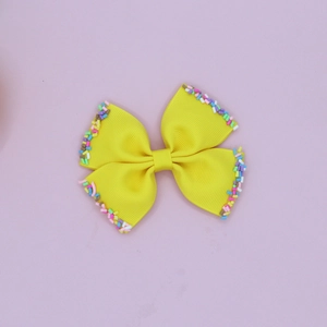 Macro detail of yellow ribbed bow hair clip featuring colorful sugar-like beads