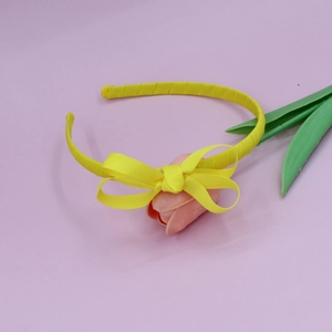 Detail of yellow ribbed grosgrain bow headband with a fine woven texture and cute style