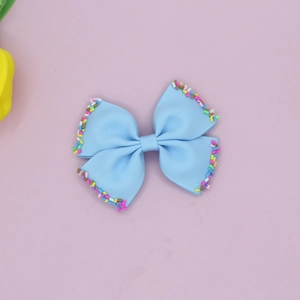 Close-up of blue grosgrain ribbon bow hair clip with colorful candy sprinkles detail