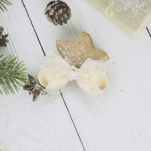 Dettaglio molletta per capelli in pizzo beige con stella di strass su legno bianco