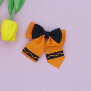 Detailed view of the layered orange and black ribbon bow hair clip with wavy line patterns
