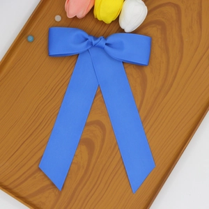 Détail d'une pince à cheveux avec nœud en ruban bleu roi et longs pans sur bois