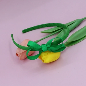 Green grosgrain ribbon headband featuring a sweet bow detail displayed on tulips