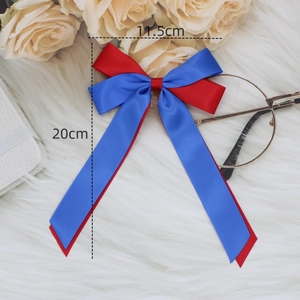 Glossy red and royal blue satin bow hair clip with long streamers on white fur background