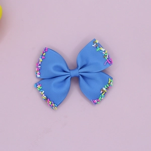 Close-up of blue grosgrain ribbon hair bow with colorful candy sprinkles on edges