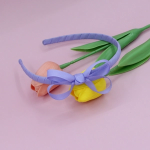 Detail of light purple ribbed bow headband on soft pink background with flowers
