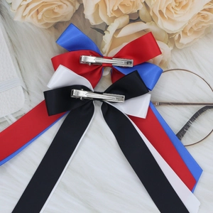 Dual-color satin ribbon bow hair clips set with long streamers on white fur carpet background