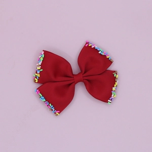 Close-up of red grosgrain ribbon hair bow with colorful candy sprinkle edges