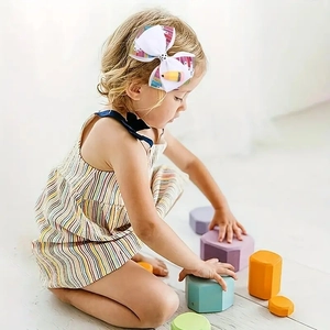 Detail of child wearing a white grosgrain ribbon hair bow with pencil print and pencil charm
