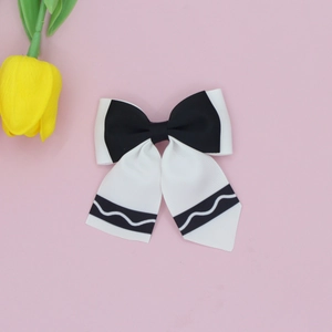 Detail of black and white bow hair clip with ribbed texture on pink background