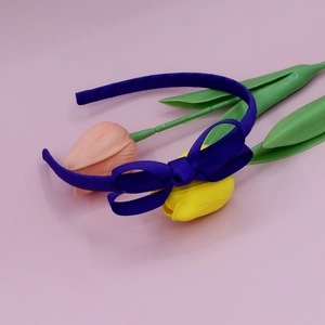 Detail of a dark purple ribbed fabric bow headband for women on a pink background