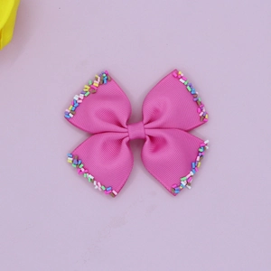 Detailed macro view of pink grosgrain bow hair clip with colorful candy sprinkle edges