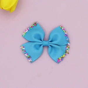 Detailed view of blue grosgrain ribbon bow hair clip with colorful sprinkles edges