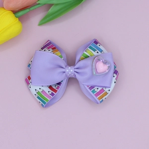 Detailed view of back to school purple hair bow with colorful pencil pattern and heart