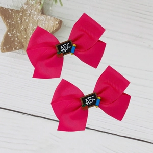 Détail de nœuds à cheveux rose avec breloques d'école comme tableau ABC et petite pomme