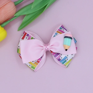 Detail of a pink bow hair clip with pencil patterns and resin pencil accent for school