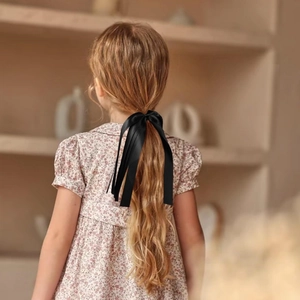 Élégant chouchou à nœud en satin noir sur la queue de cheval d'une fille pour le quotidien