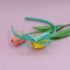 Detailed texture of mint green ribbed fabric bow headband on a soft pink background