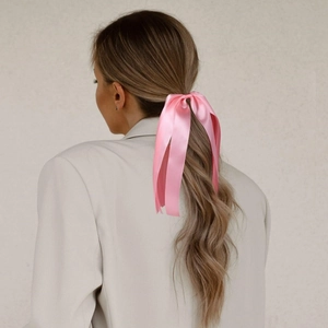 Détail d'un nœud papillon en satin rose porté sur une queue de cheval avec de longs rubans
