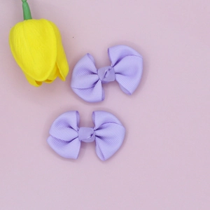 Detail view of two sweet lavender grosgrain ribbon bow hair clips on a soft pastel background