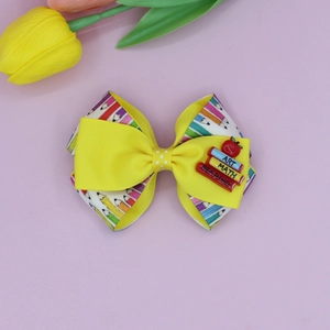Detail of yellow school bow hair clip with pencil print, mini books and red apple decor