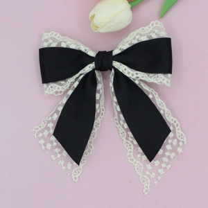 Close-up of elegant black satin and white lace bow hair clip with flowing ribbons