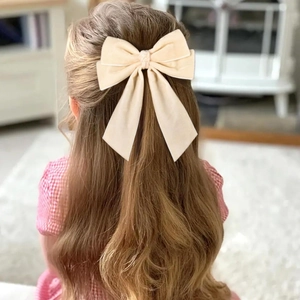 Dettaglio del fiocco in velluto crema con nastri lunghi sui capelli di una bimba