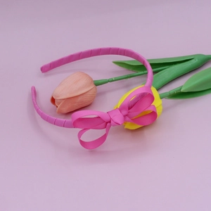 Detail of pink grosgrain ribbon headband with a delicate bow on a soft floral background