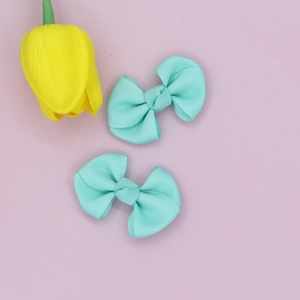 Detail view of two mint green ribbed ribbon hair bow clips on pink background