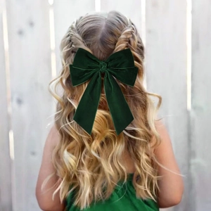 Dettaglio del fermaglio per capelli a fiocco in velluto verde scuro su capelli intrecciati