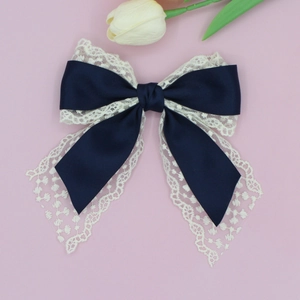 Detail of elegant navy satin and white floral lace layered bow hairpin on pink background