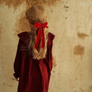 Detail of red velvet bow hair clip with long ribbons styled on a woman's hair