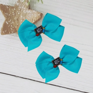 Détail de barrettes nœuds bleus avec tableau ABC et pomme pour la rentrée scolaire