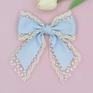 Close-up of sky blue satin bow hair clip with white floral lace trim for women