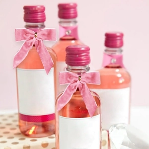 Détail d'un petit nœud en velours rose sur une bouteille en verre avec étiquette
