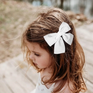 Barrette à cheveux élégante en velours blanc avec nœud papillon portée par un modèle