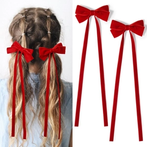 Vue détaillée de barrettes nœuds en velours rouge avec longs rubans sur modèle et fond blanc