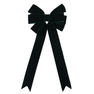 Close-up of a dark green velvet Christmas bow decoration with long hanging ribbons