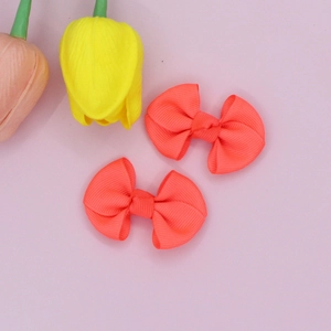 Close-up of a pair of coral ribbed ribbon hair bow clips with decorative tulips