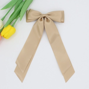 Détail d'une pince à cheveux avec nœud en satin champagne et longs rubans élégants