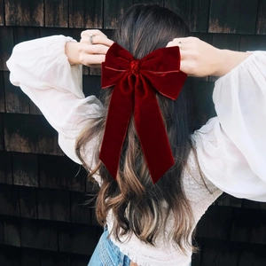 Elegant red velvet bow hair clip with long ribbons shown on long wavy hair back view