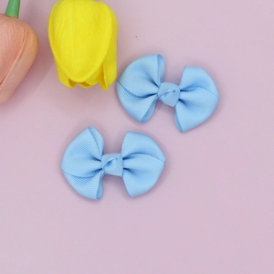 Detail of light blue grosgrain ribbon bow hair clips on a soft pink background