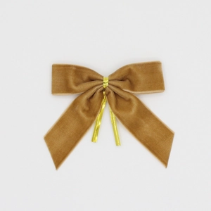 Détail de nœuds de Noël en velours beige avec attaches dorées pour cadeaux et décorations