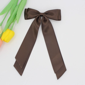 Détail d'un nœud papillon en satin marron foncé avec de longs rubans fluides élégants