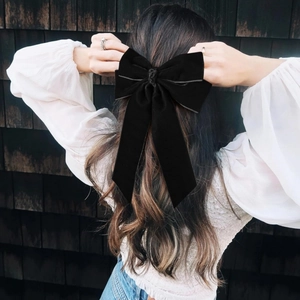 Elegant large black velvet bow hair clip with long ribbons shown on a model's hair