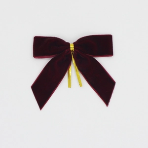 Détail de nœuds de Noël en velours rouge avec attaches dorées pour emballages de cadeaux