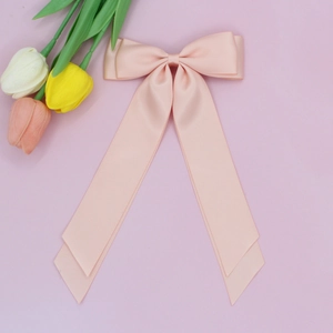 Gros plan sur l'élégante pince à cheveux en satin rose abricot avec de longs rubans